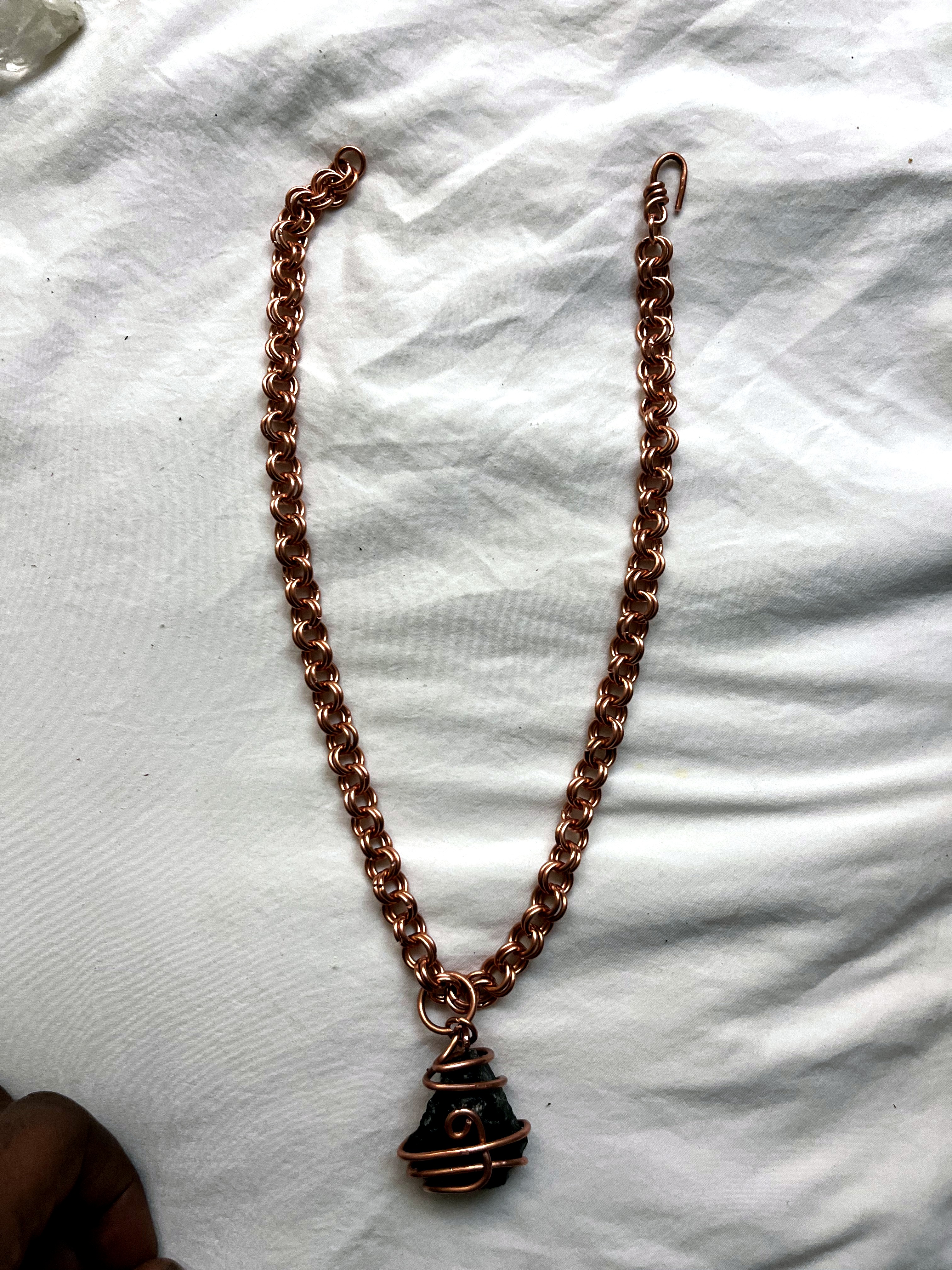 Byzantine copper chain with caged dark stone pendant on white background